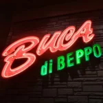 A lit up Buca di Beppo neon lettered sign