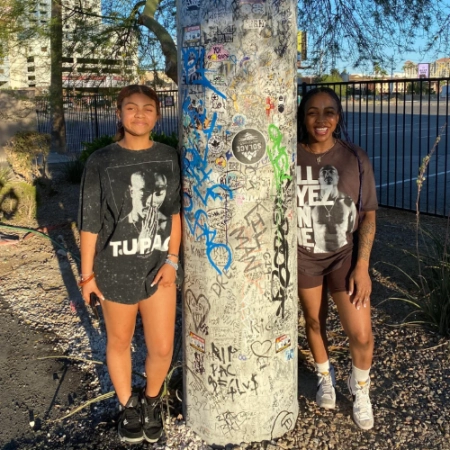 In this picture there are two women standing next to the Tupak Shakur Memorial in Las Vegas on Flamingo and Koval Rd