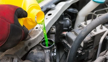 A person is adding engine coolant before a smog check